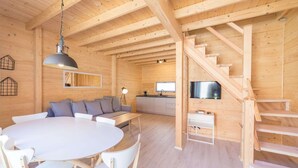 L’intérieur d’un chalet en bois comprend un coin repas, un canapé, une cuisine et un escalier.