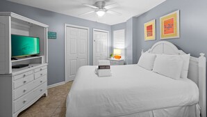 A bedroom with a bed, a TV, a ceiling fan, and a dresser. - Amalfi Coast 108A- Community Pool, Great Amenities, Steps to Beach! (Miramar Beach)