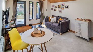A cozy living room with a grey sofa, yellow chairs, a small white table, and a cabinet. - 1 bedroom accommodation in Ryde (Ryde)