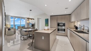 A modern kitchen with a central island, stainless steel appliances, and a view of the sea. - Lyfe Resort and residences, Ocean Front 35th floor, great views guaranteed! (Hollywood)