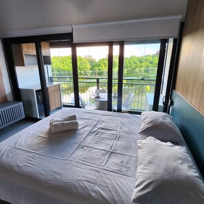 Relax in a serene room with a large bed and stunning views of a lush landscape and body of water.