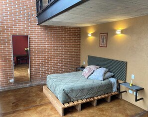 A bedroom with a brick wall, a bed with a wooden frame, two bedside tables, and a small window. - Encantador Bungalo en el Bosque (Valle de Bravo)