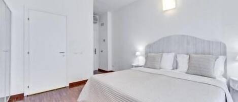 A bedroom with a bed, a wardrobe, and a nightstand.