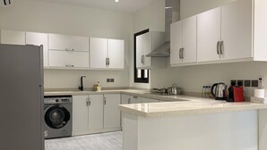 Een moderne keuken met witte kastjes, een geïntegreerde wasmachine en een granieten aanrecht.