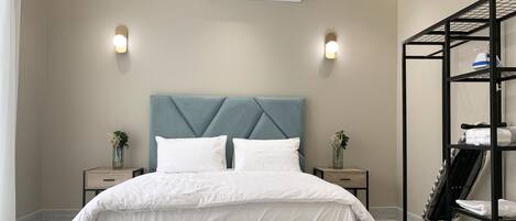 A modern bedroom with a bed, bedside tables, an air conditioning unit, and a built-in shelving unit.