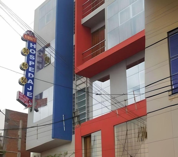A multi-story building with a prominent blue vertical stripe and a sign indicating it is a hotel.