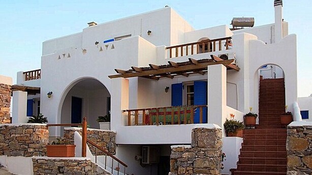 A white building with a stone staircase and a wooden pergola. - Dafnis Koufonisia (Naxos)