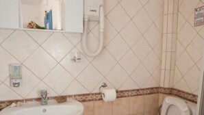 A small bathroom with a sink, toilet, and shower. - Dafnis Koufonisia (Naxos)