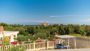 A coastal view with a stone building, lush greenery, and a clear sky. - DON LEONARDO PRIVATE POOL VILLAS (Polignano a Mare)