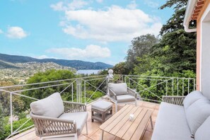A balcony with wicker furniture and a view of a hilly landscape. - Villa Tanit - Swimming pool, sea view - 10 people (Le Lavandou)