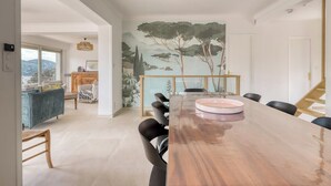 A spacious dining area with a long wooden table, black chairs, and a glass partition. - Villa Tanit - Swimming pool, sea view - 10 people (Le Lavandou)