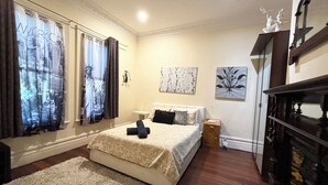 Un dormitorio con cama, mesita de noche, cómoda y ventana con cortinas.