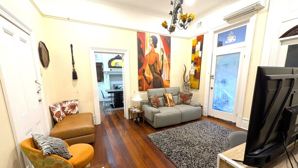 Una sala de estar con un sofá, un televisor, una mesa de centro y una alfombra.