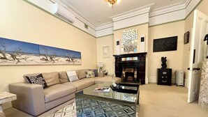 A living room with a beige sofa, a glass coffee table, and a patterned rug. - Subiaco Heritage House "Gem"! (Shenton Park)
