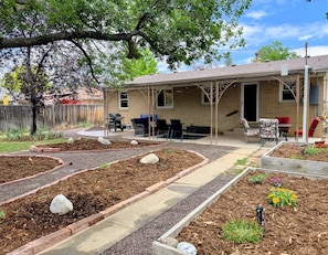 A residential backyard with a patio, outdoor furniture, and a garden area.