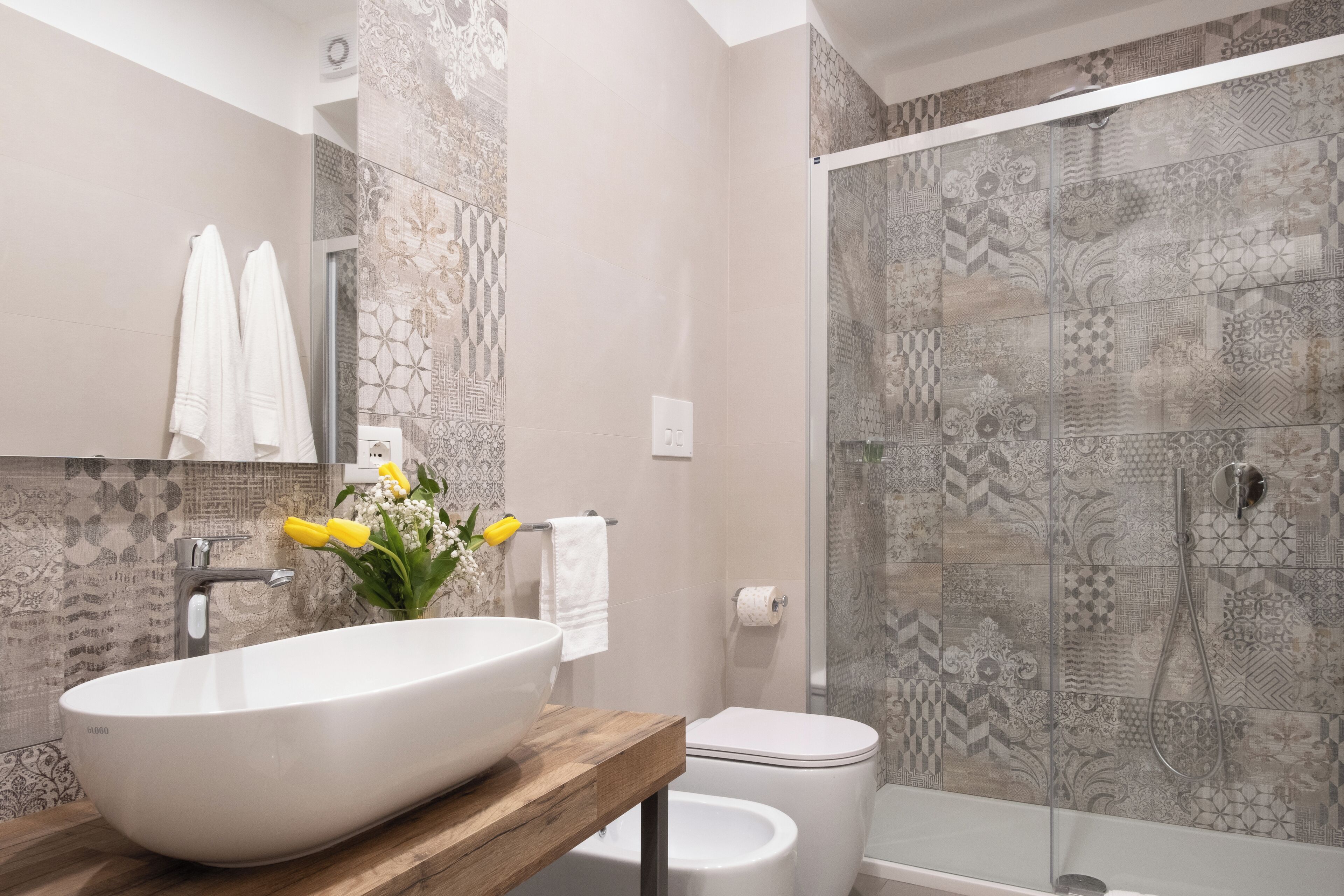 Een moderne badkamer met een groot wit wastafel, toilet en douchecabine.
