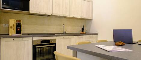 A modern kitchen with wooden cabinets, a built-in oven, a microwave, and a dining area with a table and chairs.