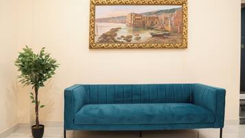 Un canapé de couleur turquoise, une plante en pot et un tableau encadré accroché au mur.