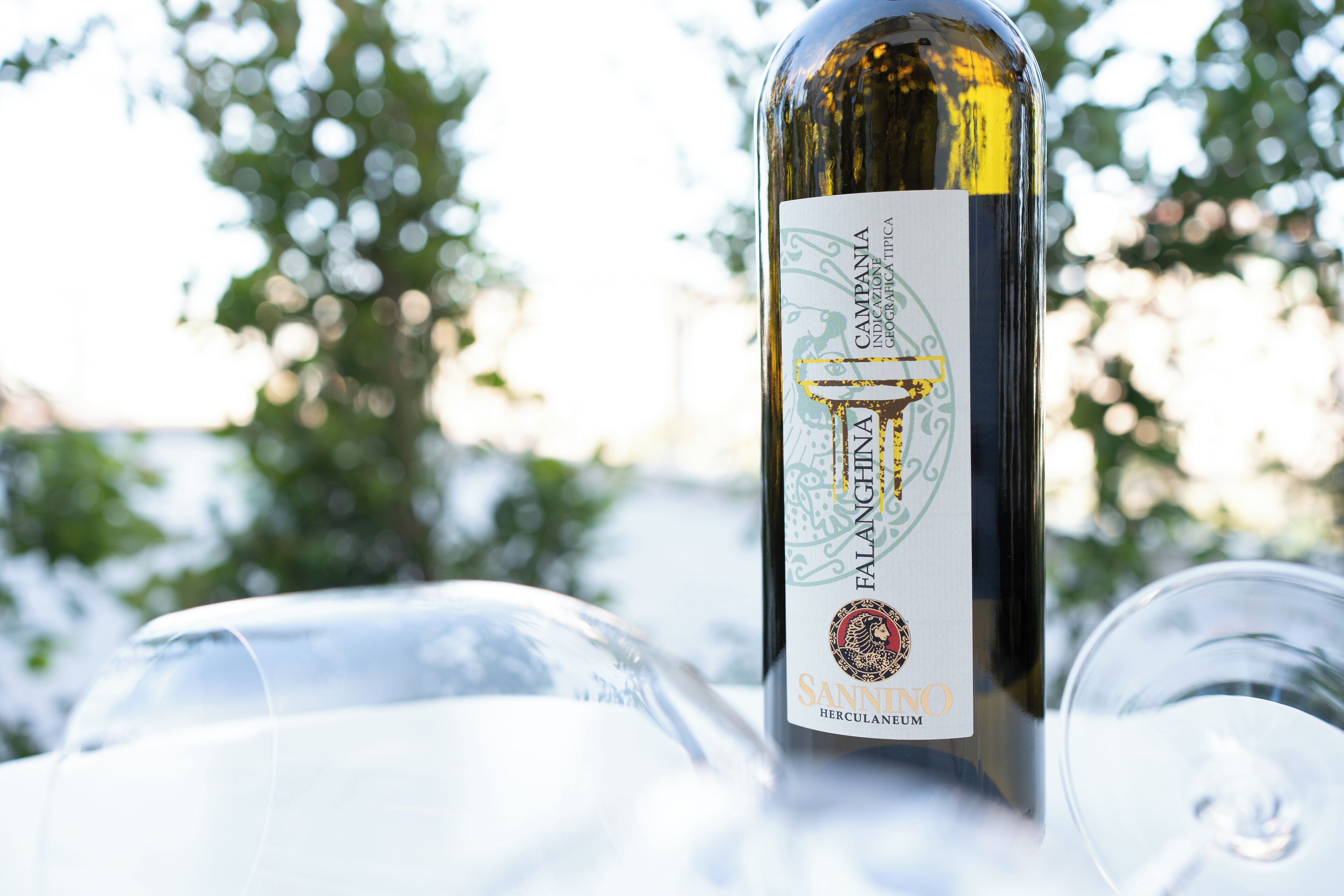 A bottle of Falanghina wine with a label, placed on a table with clear glass wine glasses.