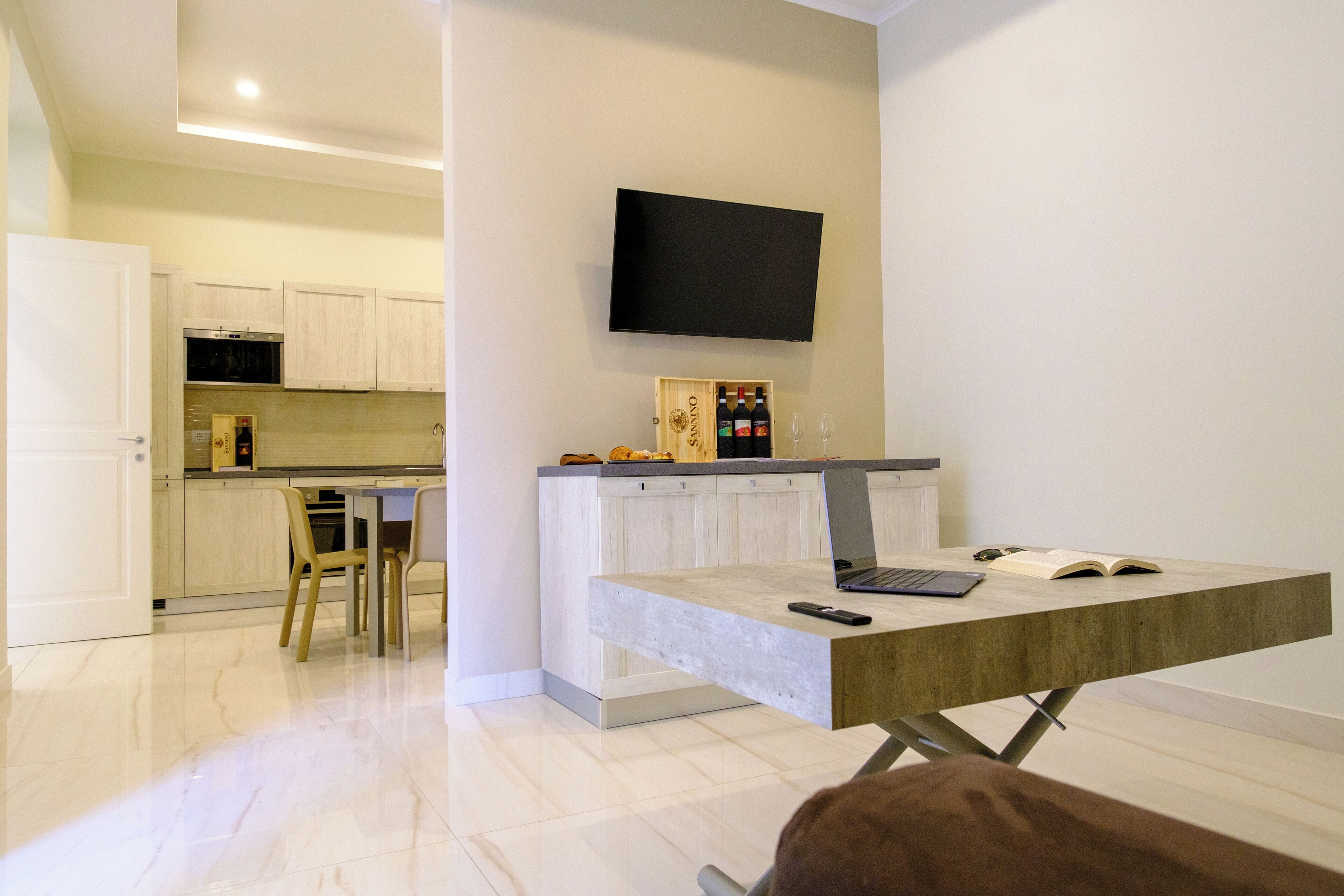 A modern kitchen with white cabinets, a built-in oven, and a TV mounted above the counter.