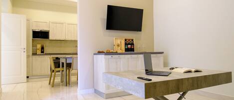 A modern kitchen with white cabinets, a built-in oven, and a TV mounted above the counter.