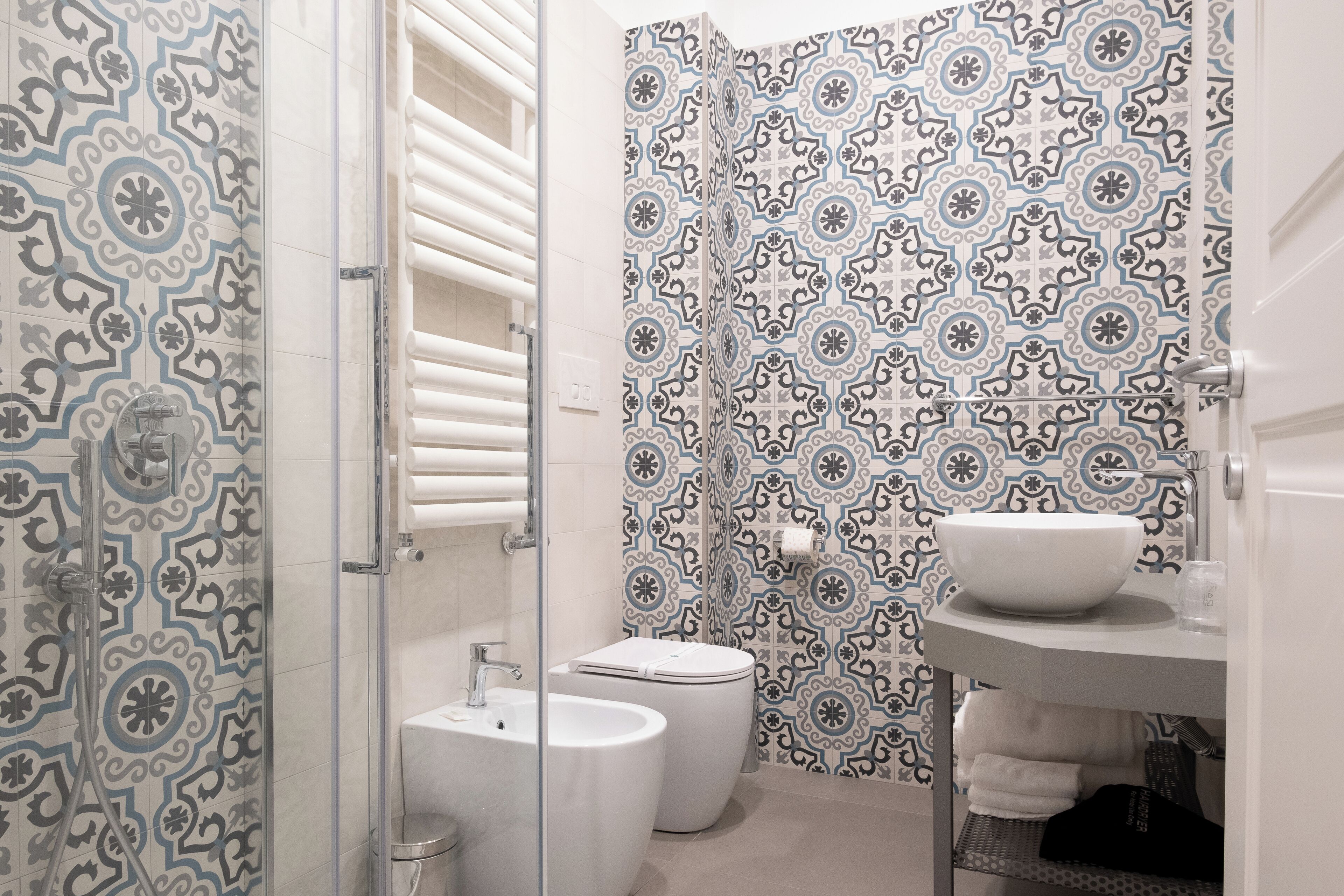 A bathroom with patterned tiles, a white sink, and a toilet.