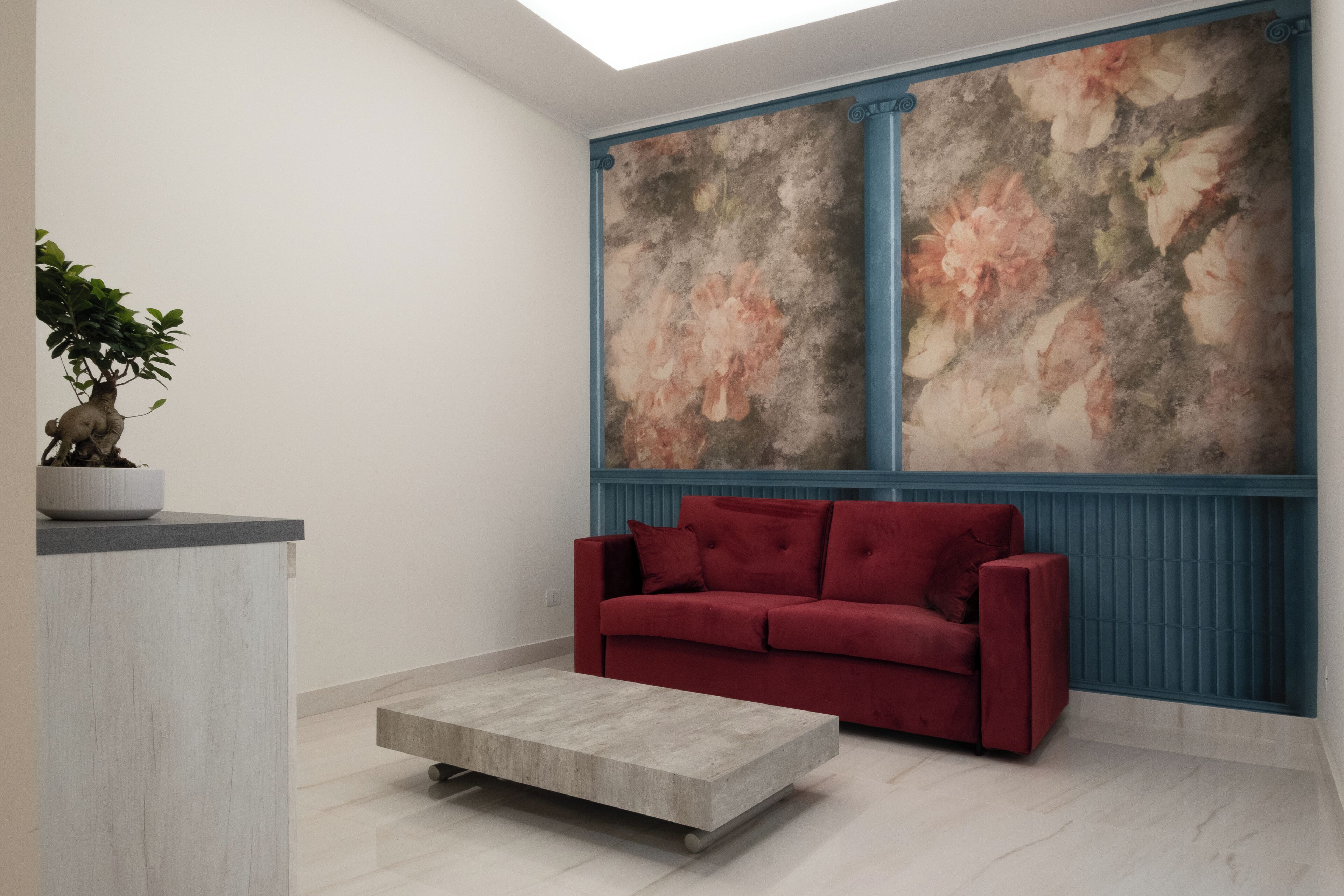 Una sala de estar moderna con un sofá rojo, una mesa de centro de hormigón y una planta en maceta.