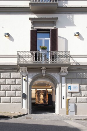 A building entrance with a balcony, a door, and a sign indicating 'Palazzo Adele'.