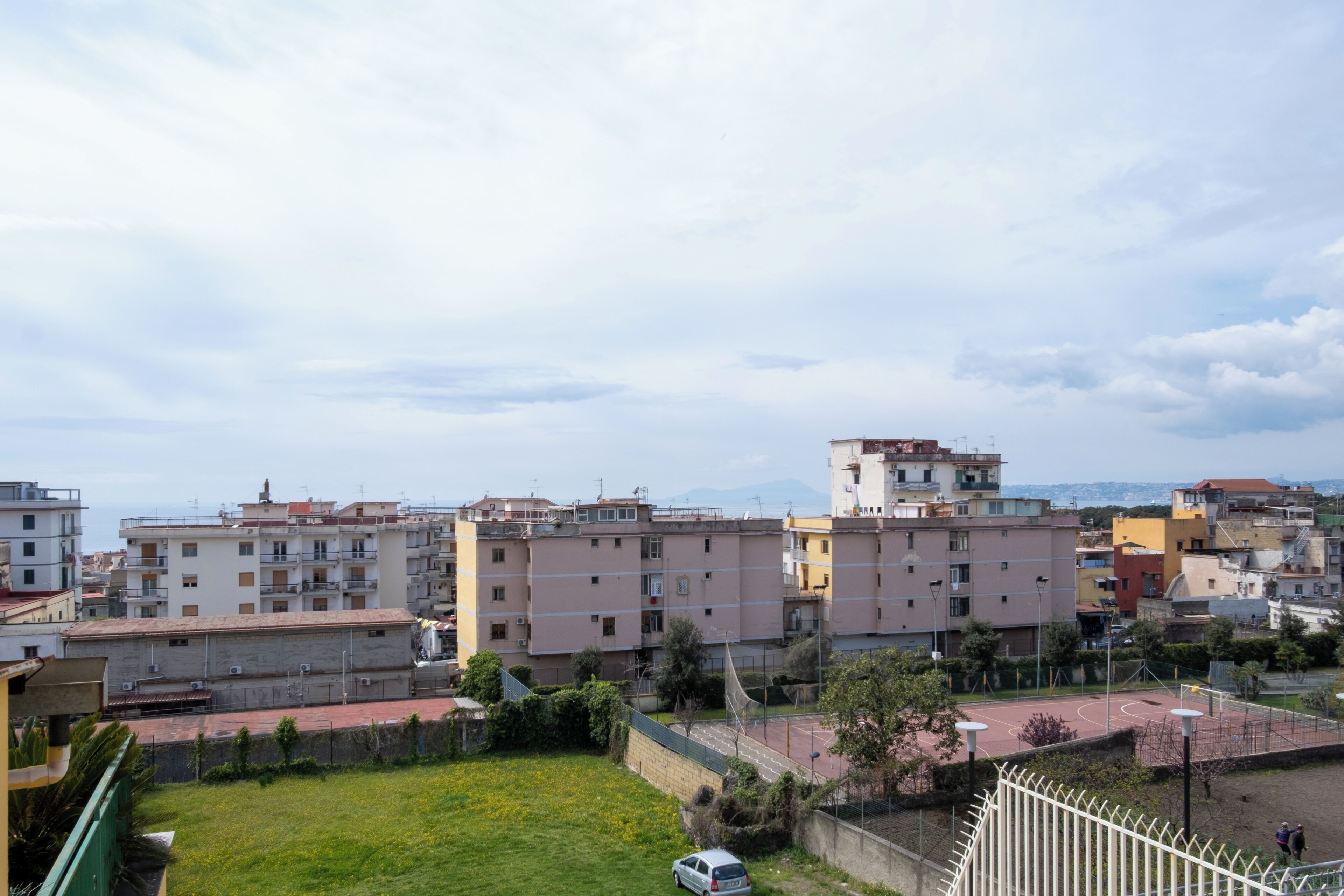 Un quartiere residenziale con edifici a più piani, uno spazio verde e un campo da basket.