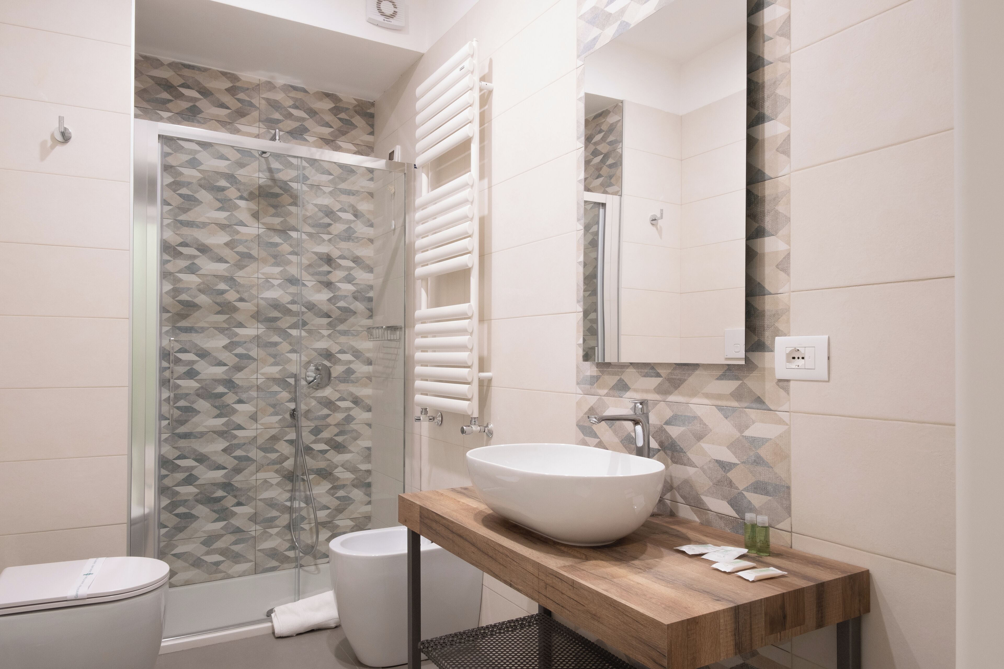 A modern bathroom with a glass-enclosed shower, a wooden vanity with a white sink, and a tiled backsplash.