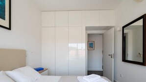 A hotel room with a bed, a wardrobe, a mirror, and a small table with a blue object on it. - Apt. dos Correios, a short walk to the town center (Lagos)