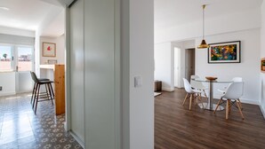 A modern apartment with a sliding door, a dining area with a glass table, and a view of the city through large windows. - Apt. dos Correios, a short walk to the town center (Lagos)