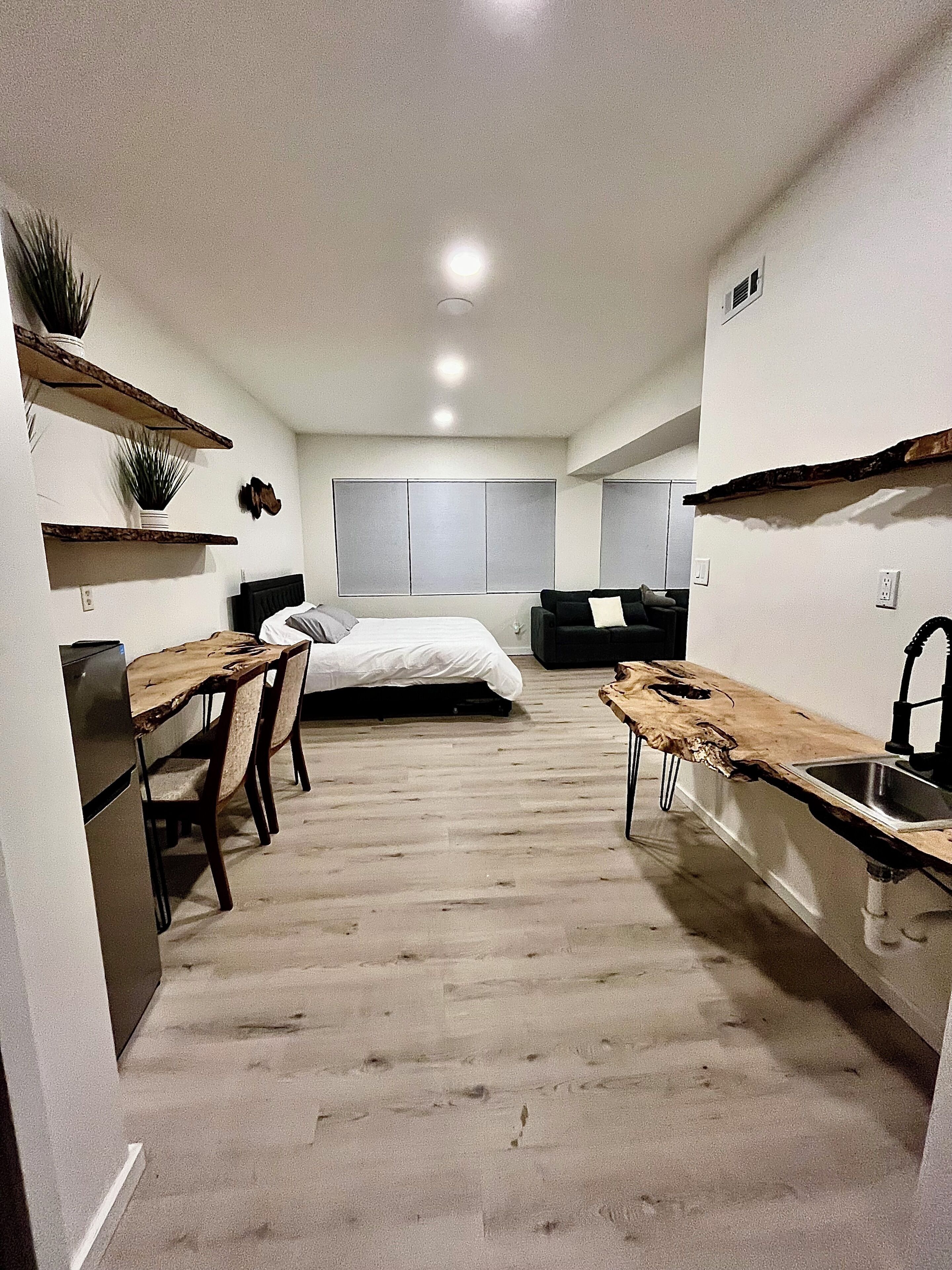 A compact, modern apartment with a kitchenette, a dining area, and a bed.