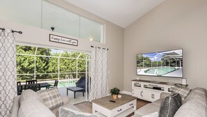 A modern living room with a large window, a flat-screen TV, and a comfortable seating area.
