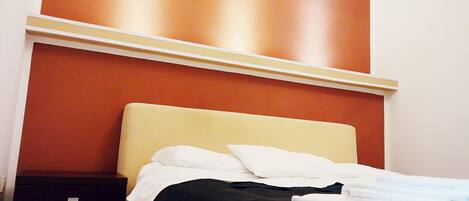 A bed with a beige headboard, white pillows, and a dark blue bedspread.