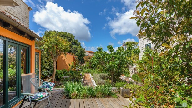 A wooden deck with chairs, a stone pathway, and lush greenery. - Dubrovnik art Gateway (Dubrovnik)