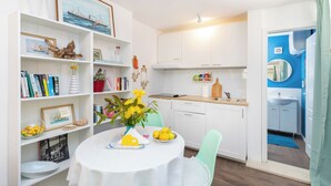 A modern kitchen with white cabinets, a dining table with a white tablecloth, and a blue accent wall. - Dubrovnik art Gateway (Dubrovnik)