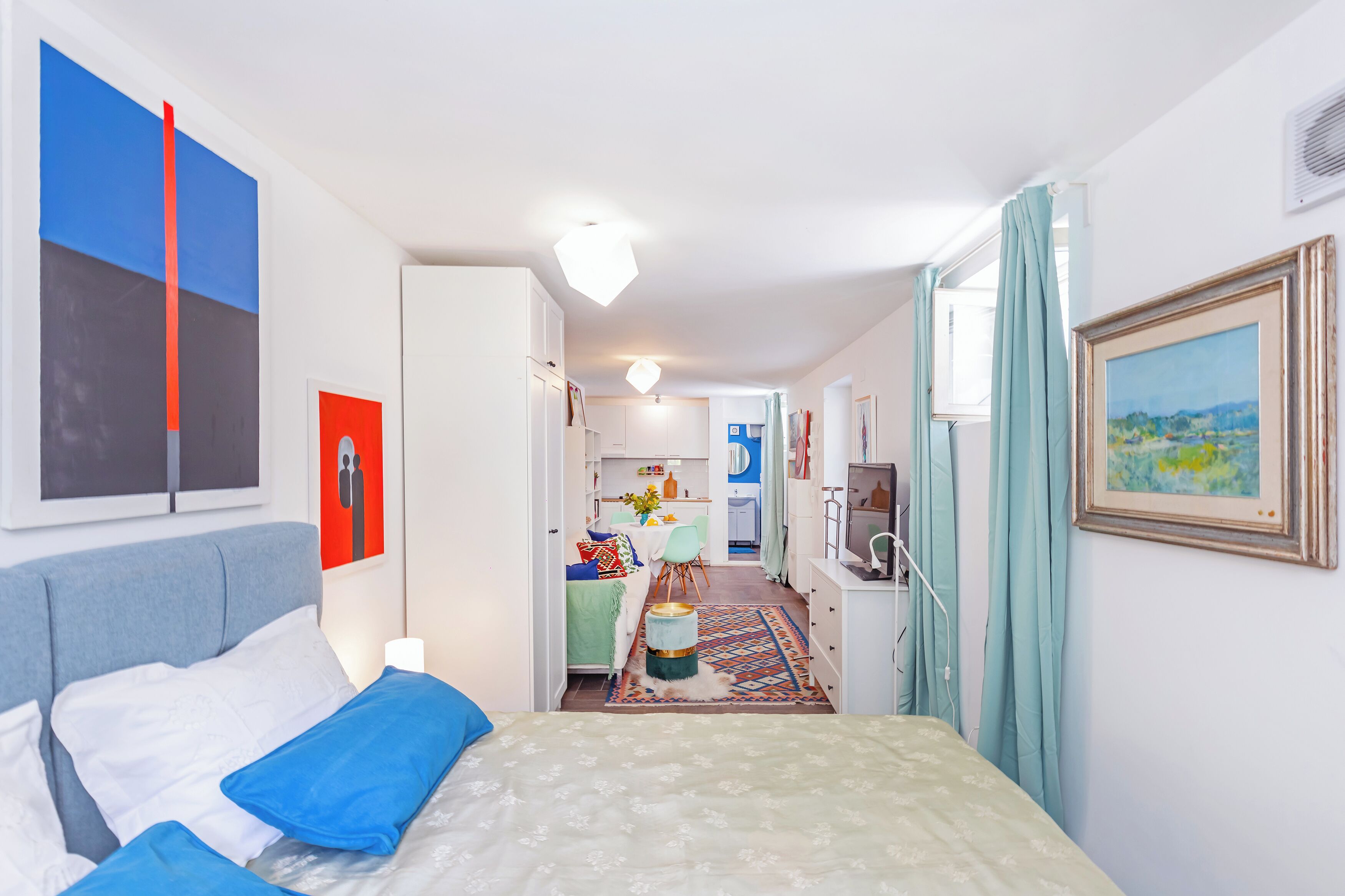 A hotel room with a bed, a desk, and a kitchenette.
