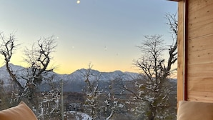 Una habitación con dos sillas frente a un ventanal que da a un paisaje montañoso cubierto de nieve.