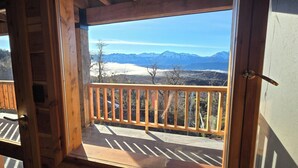 Un balcón de madera con vistas a montañas nevadas y un cielo despejado.