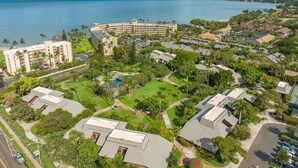 Luchtbeeld van een resort met meerdere gebouwen, een zwembad en een groot waterlichaam op de achtergrond.