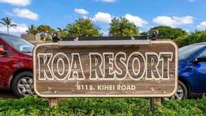 Een houten bordje voor KOA RESORT met het adres 811 S. KIHEI ROAD.