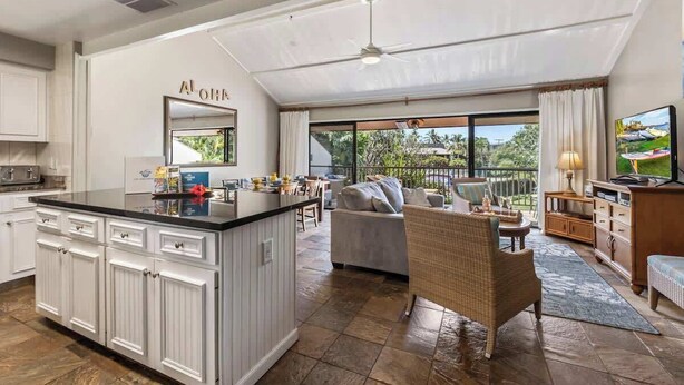 Een ruime keuken met een groot eiland, een zithoek met een bank en stoelen, en een balkon met uitzicht.