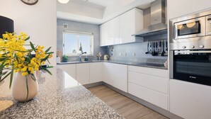 A modern kitchen with white cabinets, a Bosch oven, and a window with a view. - Apt. Deluxe OCV - Pool & Albufeira View (Albufeira)