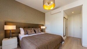 A modern bedroom with a large bed, two bedside tables with lamps, a wardrobe, and a ceiling light fixture. - Apt. Deluxe OCV - Pool & Albufeira View (Albufeira)