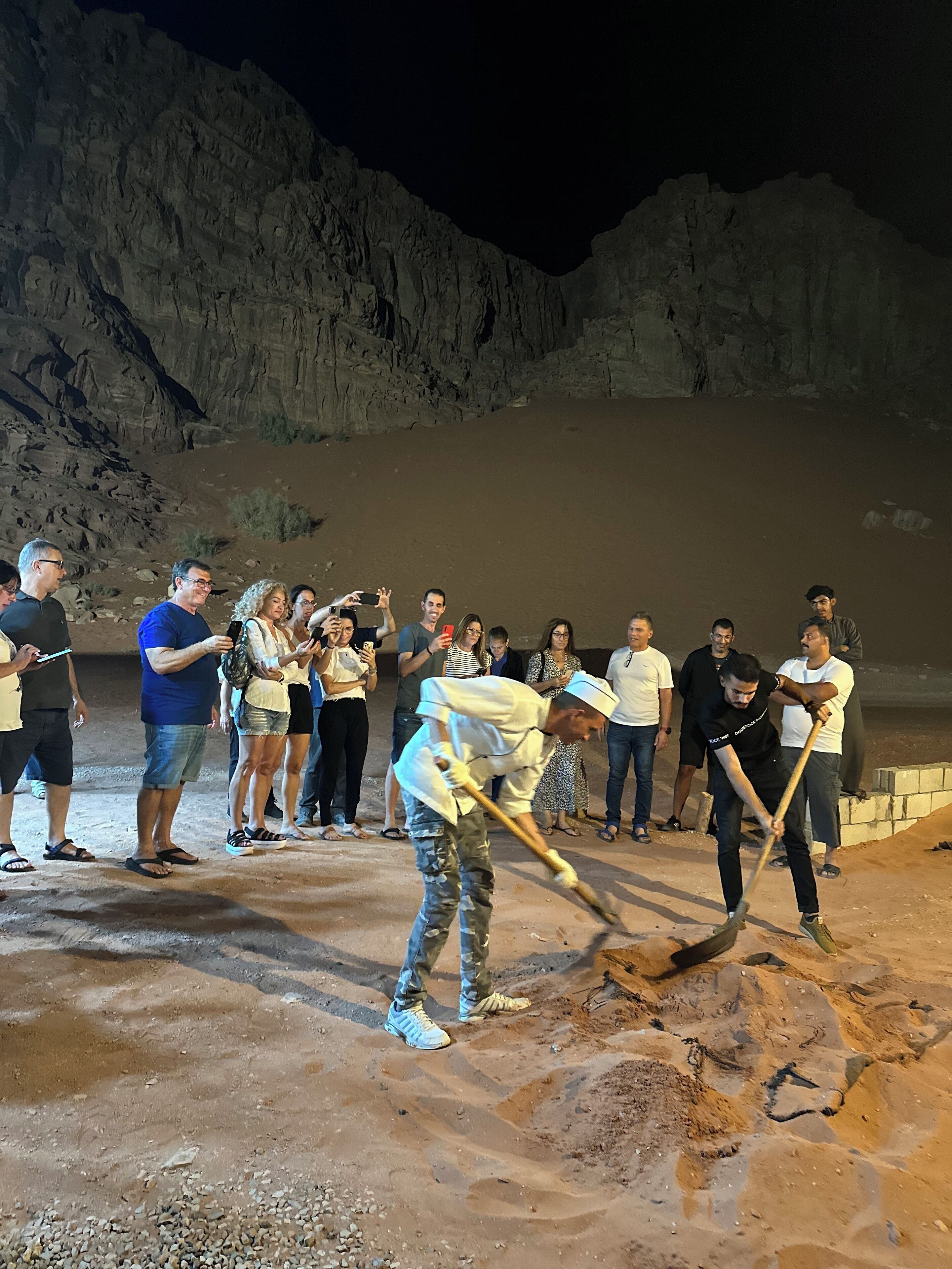 Un grupo de personas observando a un hombre removiendo arena.