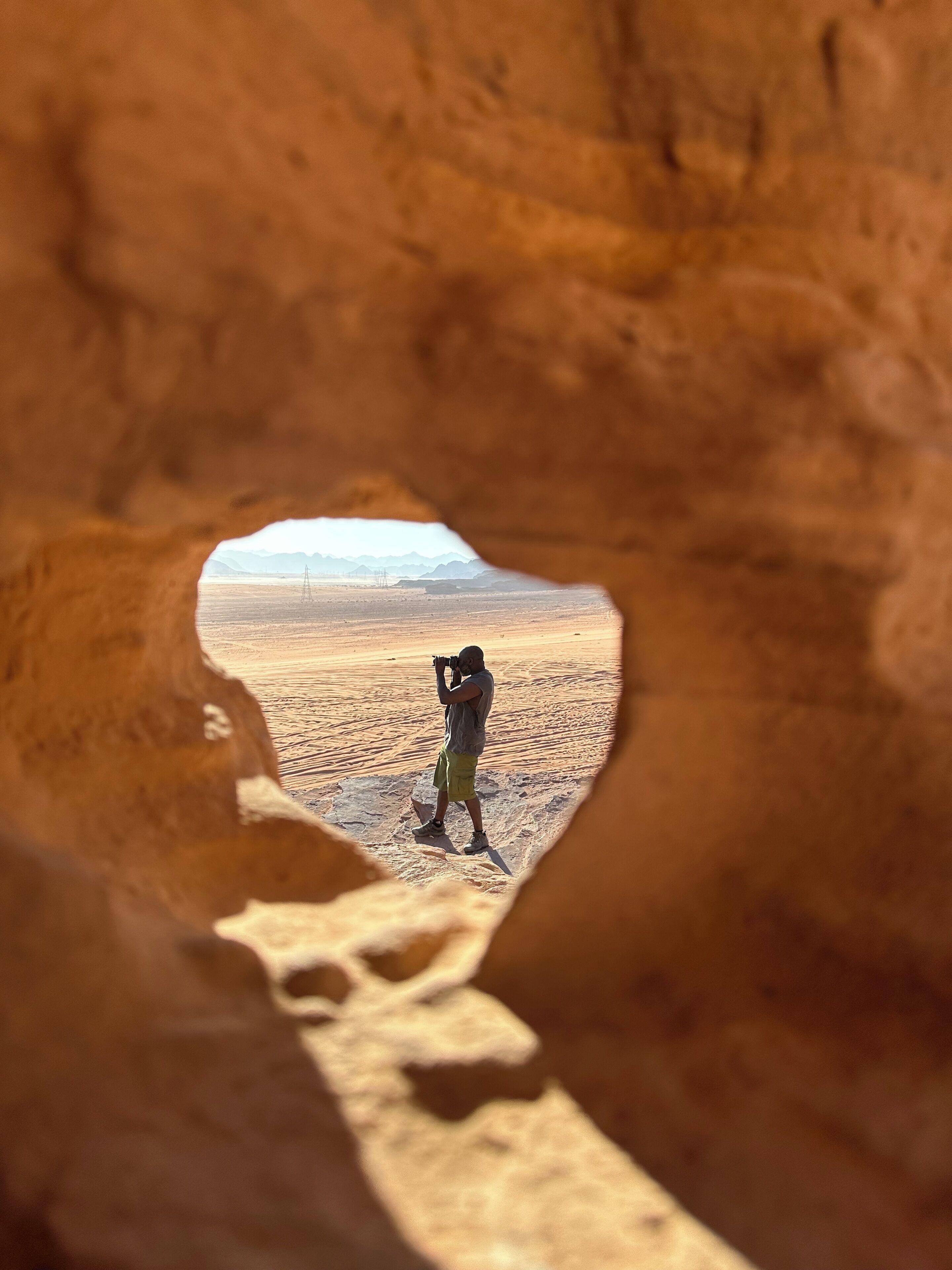 Une personne prend une photo à travers l’ouverture d’une grotte.