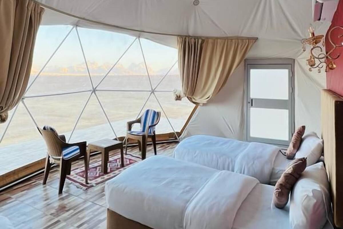 A tented room with a bed, a chair, and a table.