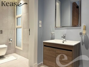 Un baño moderno con un lavamanos blanco, un espejo y un inodoro.