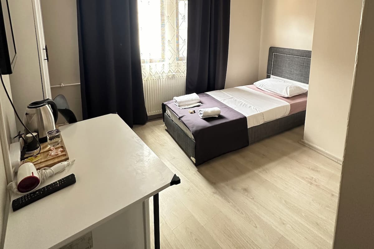 Ein kleiner, ordentlich eingerichteter Raum mit einem Bett, einem Schreibtisch und einer Heizung.